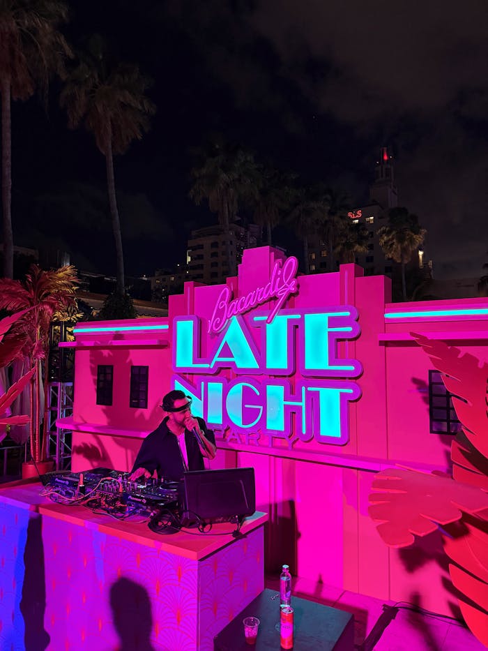 Nighttime DJ set with neon lights and tropical vibes creating a vibrant party atmosphere.