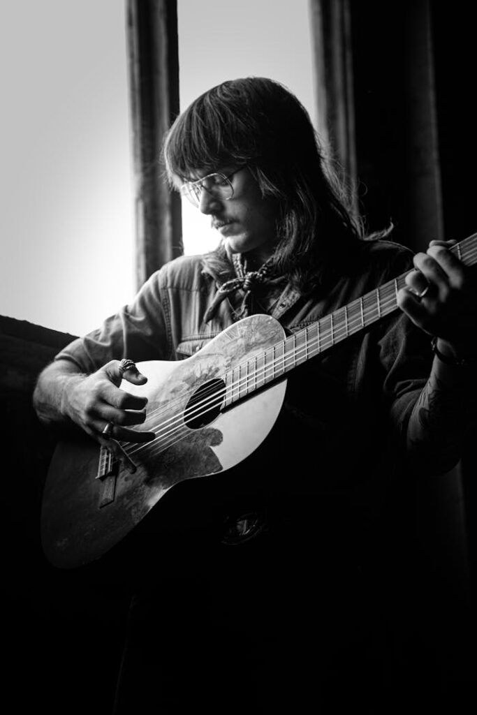 Il conduttore di DC Notte: talento e passione Artistic black and white portrait of a guitarist playing indoors, NSW Australia.